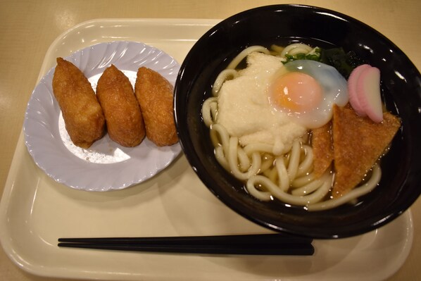 Uma bandeja com uma tigela de macarrão ramen coberto com ovo, rabanete e vegetais verdes, e um prato com quatro alimentos fritos.