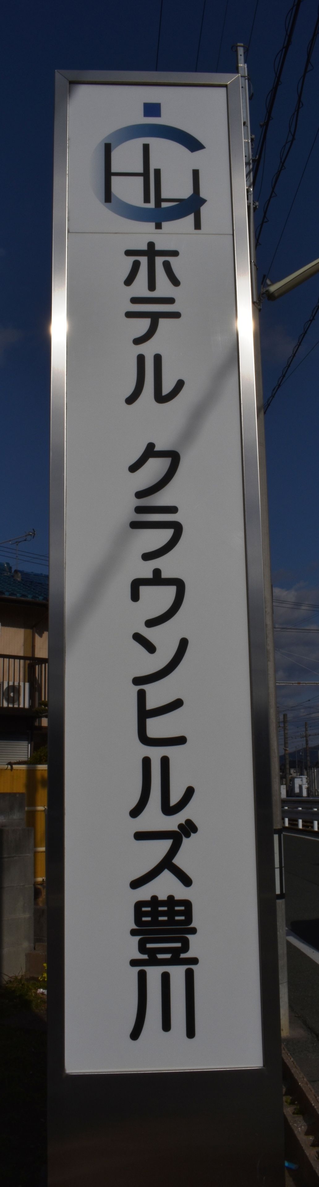 Uma placa vertical com caracteres japoneses, provavelmente indicando o nome de um estabelecimento ou local.