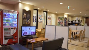 A room with a television, a Coca-Cola vending machine, seating, and a small table. - Hotel Crown Hills Toyokawa (Toyokawa)