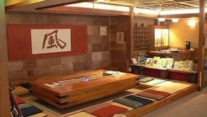 Una habitación japonesa tradicional con suelo de tatami, una mesa de madera baja y un cuadro colgado en la pared.