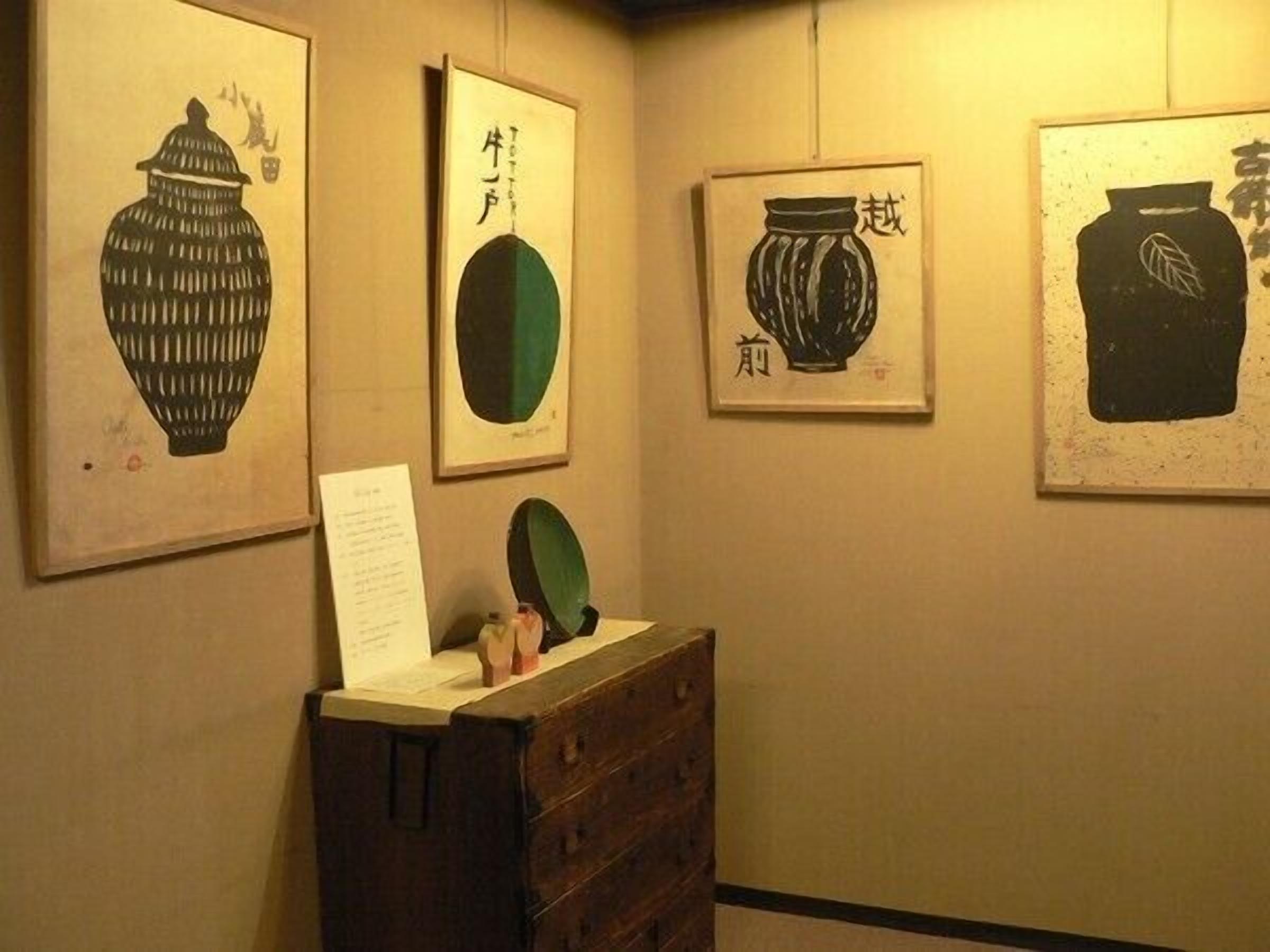 A hallway with framed artwork on the walls, a wooden dresser, and a mirror.