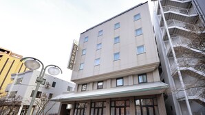 Un hôtel à plusieurs étages, doté d’une façade sobre, de grandes fenêtres et d’une entrée bien visible, avec une allée couverte menant à l’entrée.