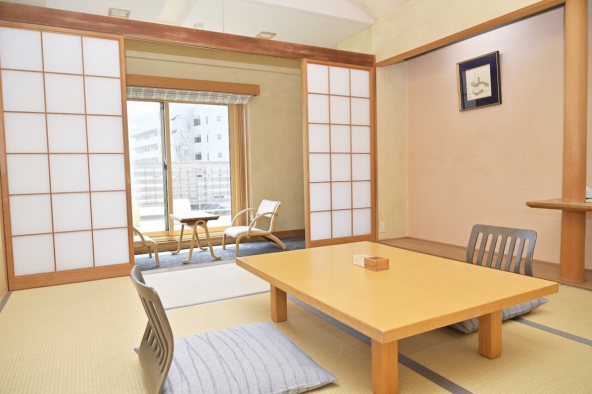 Ett traditionellt japanskt rum med tatamimattor på golvet, ett lågt bord och skjutdörrar.