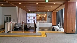 A modern building entrance with a ramp and an elevator, a security checkpoint, and a sign with various images. - Nagano Plaza Hotel (Nagano)