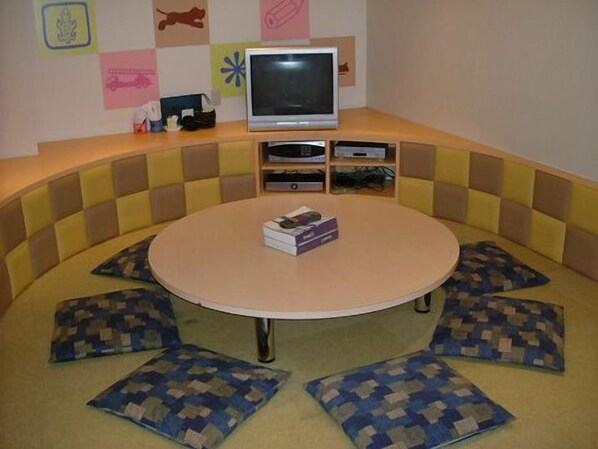 A round table with a beige tabletop surrounded by a checkered couch with blue and beige cushions.