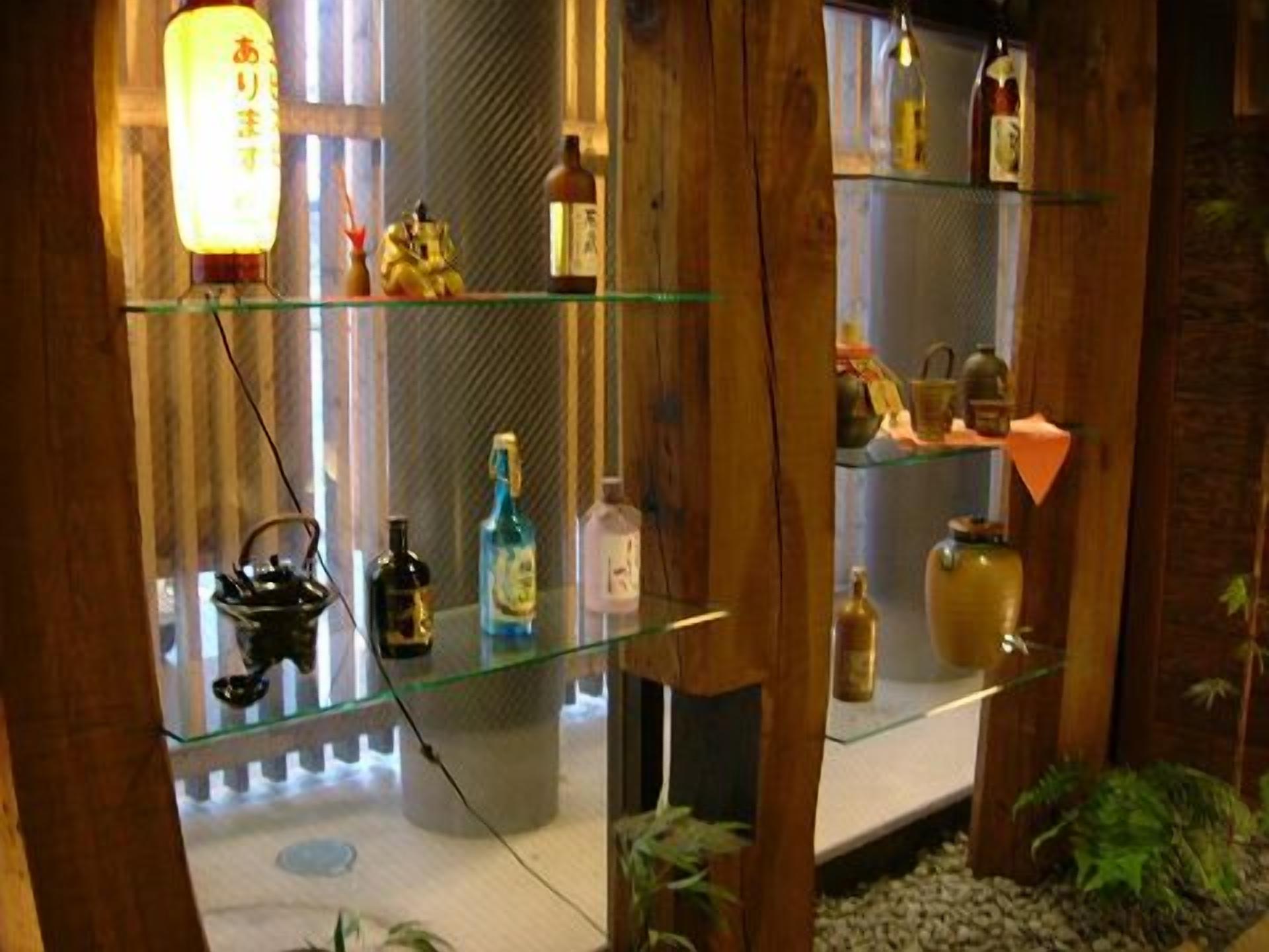 Una habitaci ón con vigas de madera, un estante de vidrio con varias botellas y una pequeña estatua.