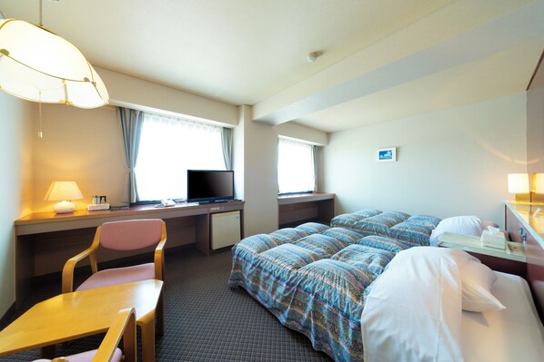A hotel room with a bed, desk, chair, television, and a window with curtains.