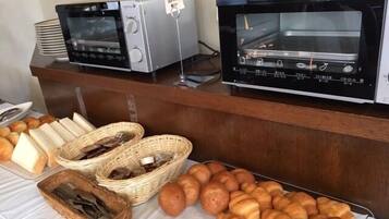 A buffet with various baked goods, including bread and croissants, and two ovens.