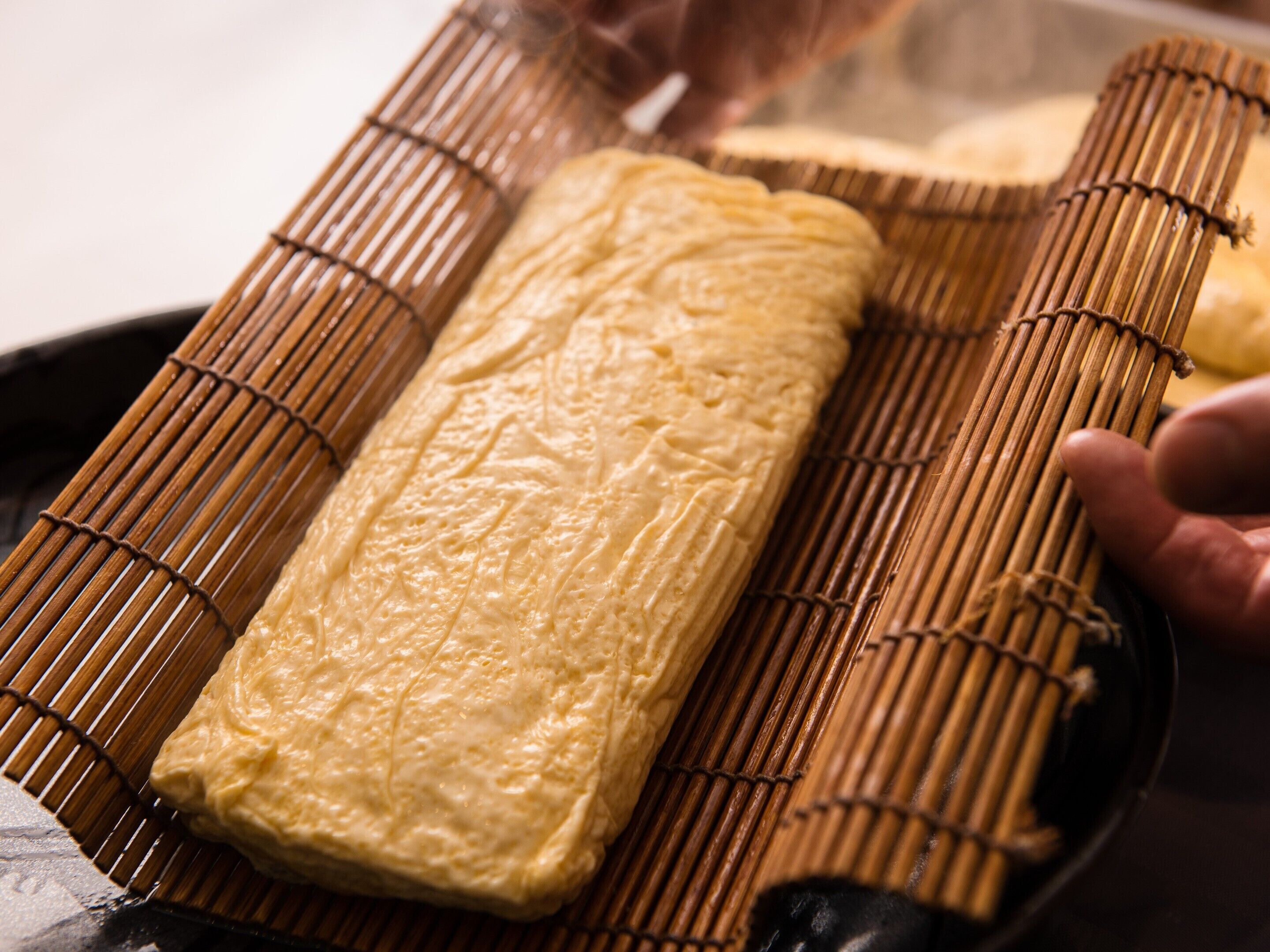 A tray with a rectangular food item, possibly a pastry, on a bamboo mat.