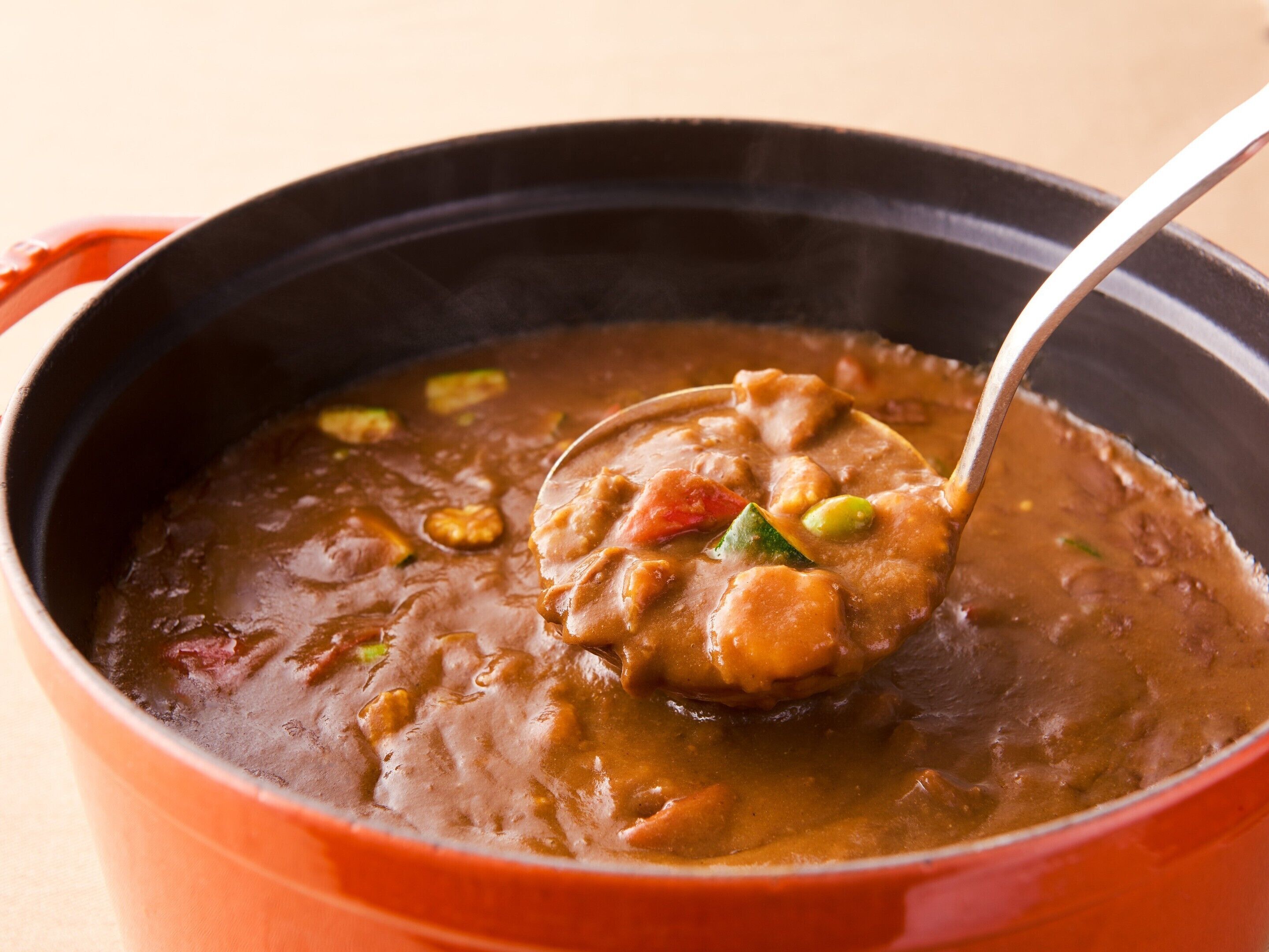 Primer plano de un guiso con trozos de carne y verduras en una olla roja.