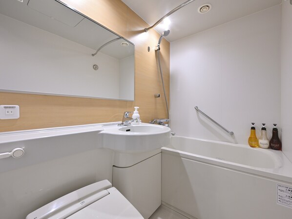 Un baño moderno con lavamanos, espejo, ducha e inodoro.
