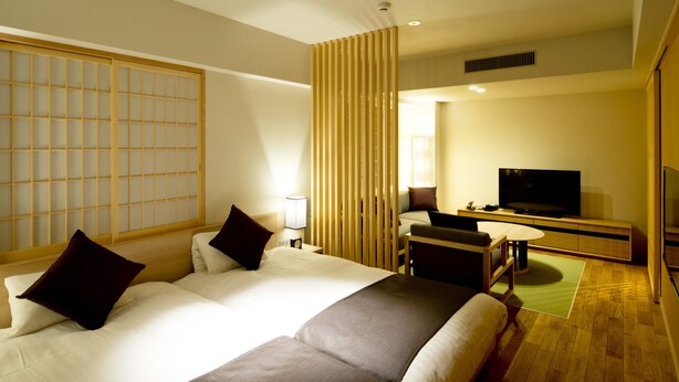 A modern hotel room with a large bed, a TV, and a desk.