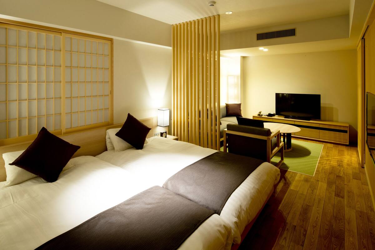 A modern hotel room with a large bed, a TV, and a desk.