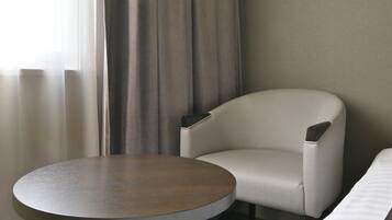 Una habitación de hotel con una mesa redonda, un sillón y una cama.