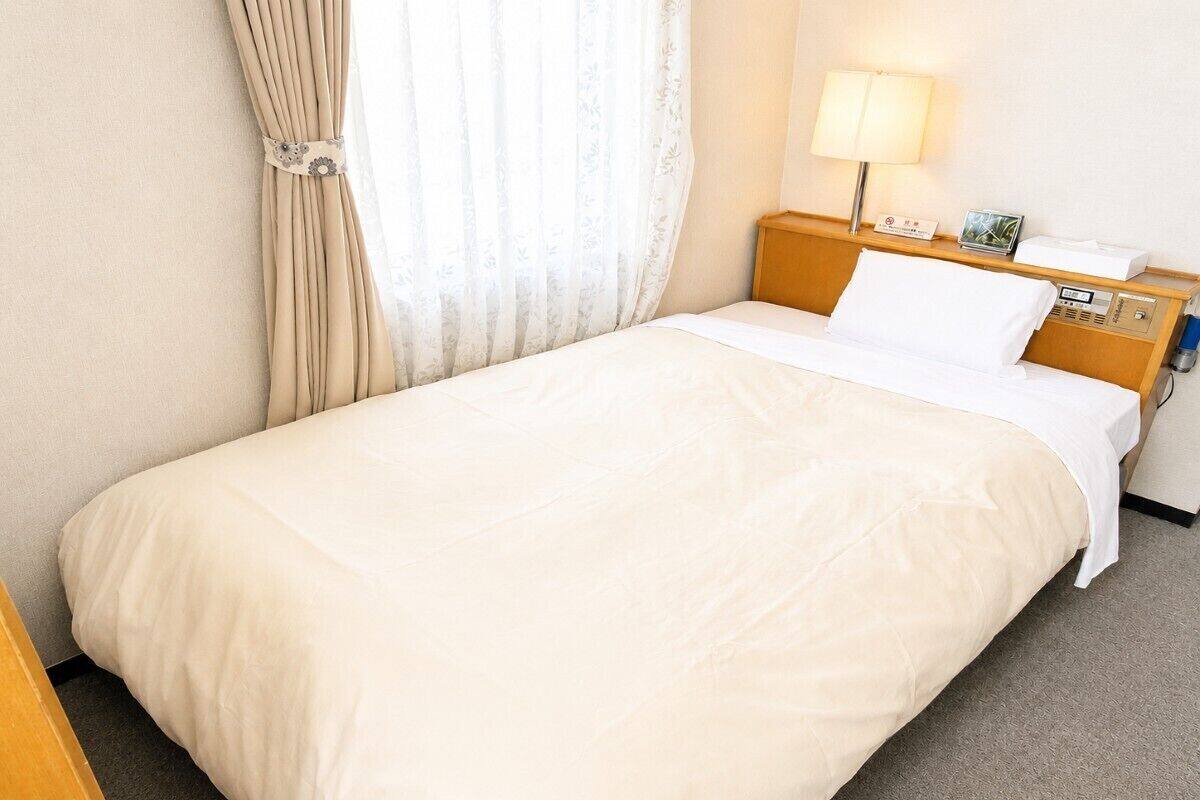 A hotel room with a bed, a nightstand, a lamp, and a clock.