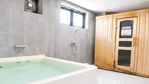 Een kamer met een groot bad, een houten deur en een raam.