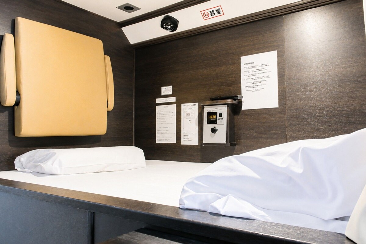 A hotel room with a bed, a control panel, and a wall-mounted cabinet.