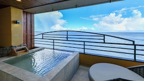 A balcony with a view of the ocean, a hot tub, and a chair. - Hokkawa Onsen Hotel (Higashiizu)