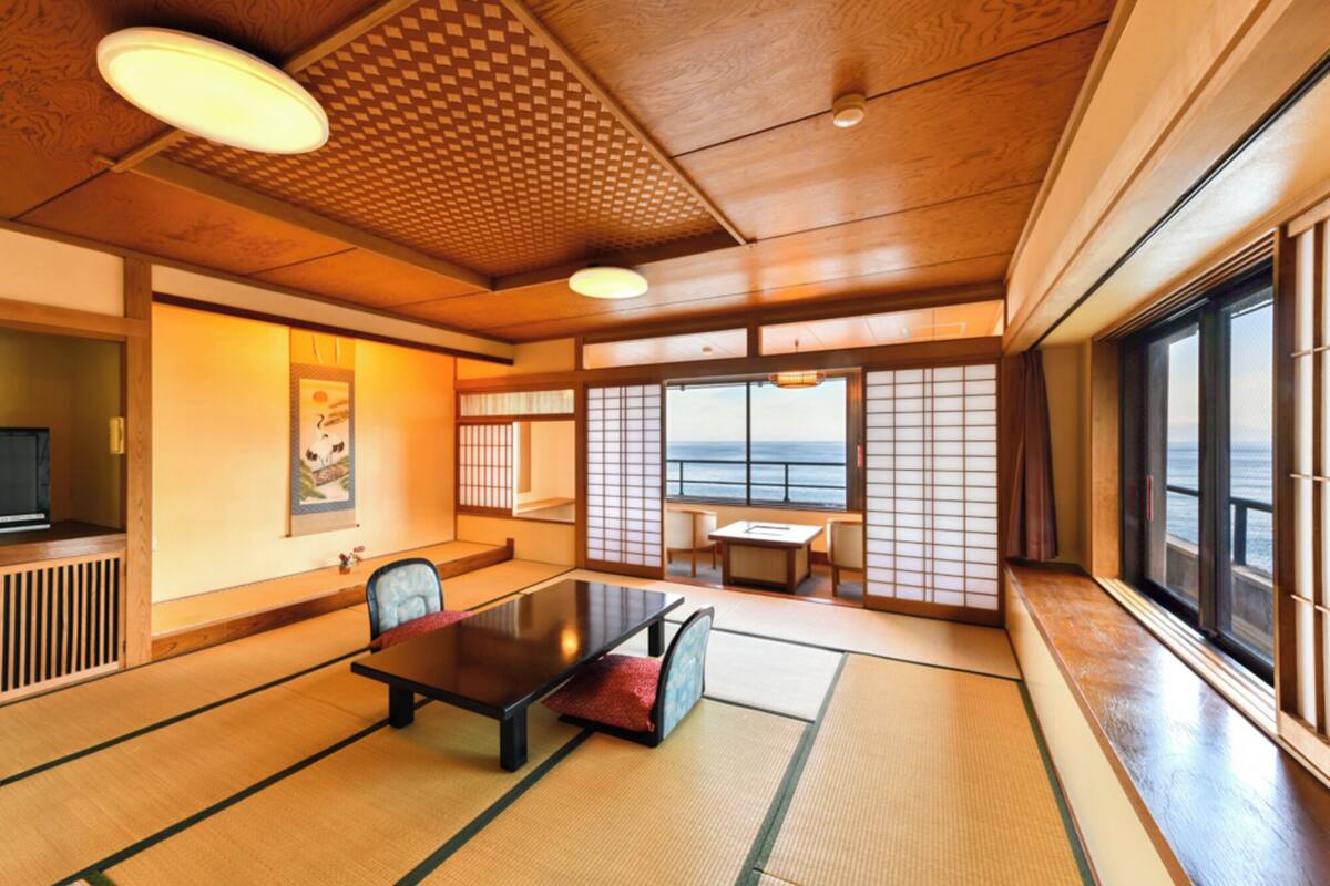 Una habitación tradicional japonesa con suelo de tatami, una mesa baja y puertas correderas.
