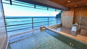 A modern indoor swimming pool with a view of the ocean, wooden walls, and a shower area. - Hokkawa Onsen Hotel (Higashiizu)