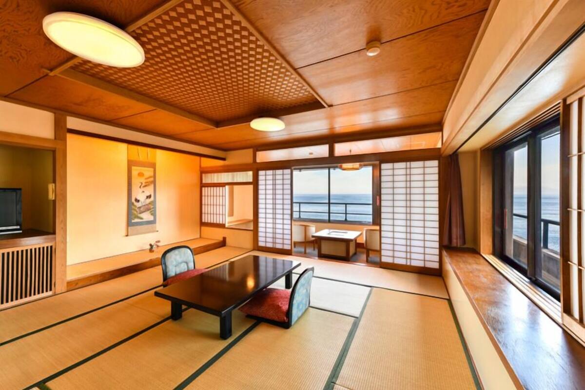 Una habitación japonesa tradicional con suelo de tatami, una mesa baja y puertas correderas.