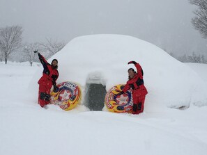 Two people in red winter clothing holding snowboards in a snowy outdoor setting.