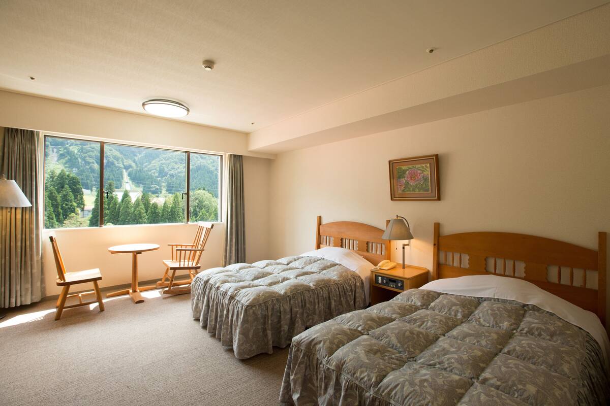 Ein Hotelzimmer mit zwei Betten, einem kleinen Tisch und einem Stuhl.