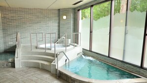 Een wellnessruimte met een jacuzzi, een klein zwembad en een glazen wand.