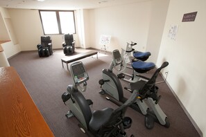 A fitness room with exercise equipment, a bench, and a whiteboard.