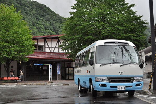 A bus parked in front of a building with a red roof and a signboard.