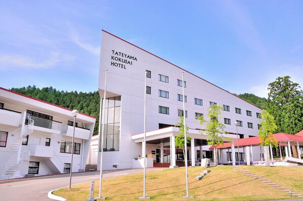 A modern hotel with a flat roof, multiple floors, and a covered entrance area.