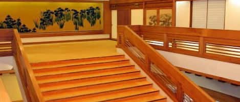 Una escalera de madera con un candelabro, un cuadro en la pared y puertas correderas tradicionales japonesas.