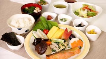 A variety of dishes including rice, vegetables, and fish, served on a table with multiple small bowls containing condiments.