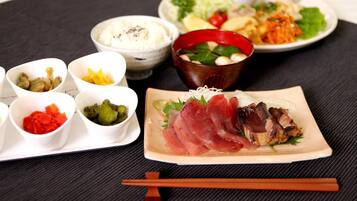 Diversos pratos, incluindo sashimi, vegetais em conserva e uma tigela de sopa sobre uma toalha de mesa preta.