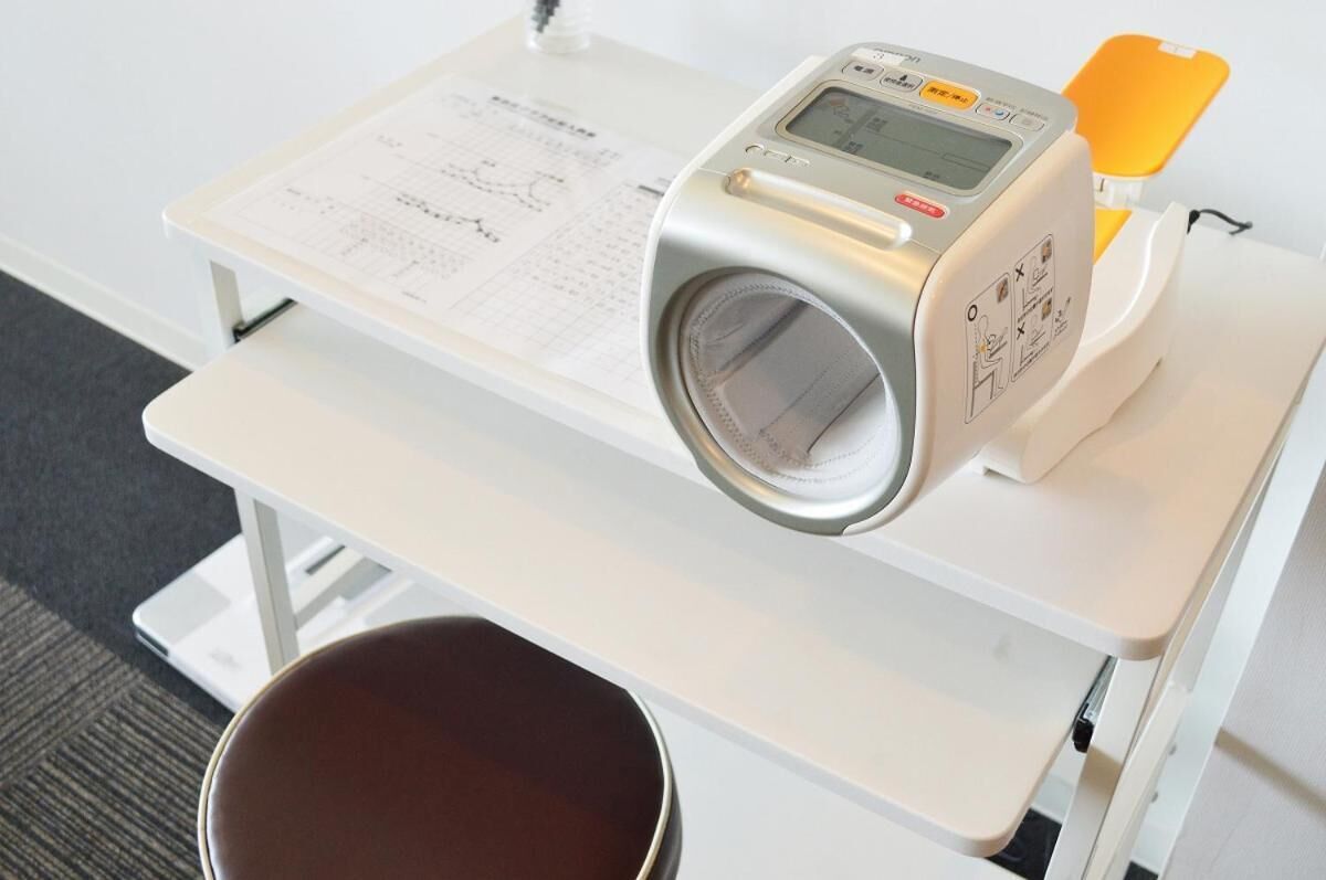 Ein medizinisches Gerät auf einem weißen Tisch, nebenan ein Dokument und ein gelbes Objekt.