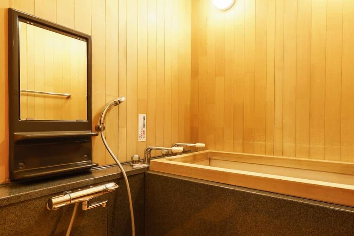 A wooden interior with a bathtub, a mirror, and a towel rack.