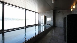 A modern indoor swimming pool with large windows, a glass barrier, and a view of the landscape. - Just ONE (Susono)