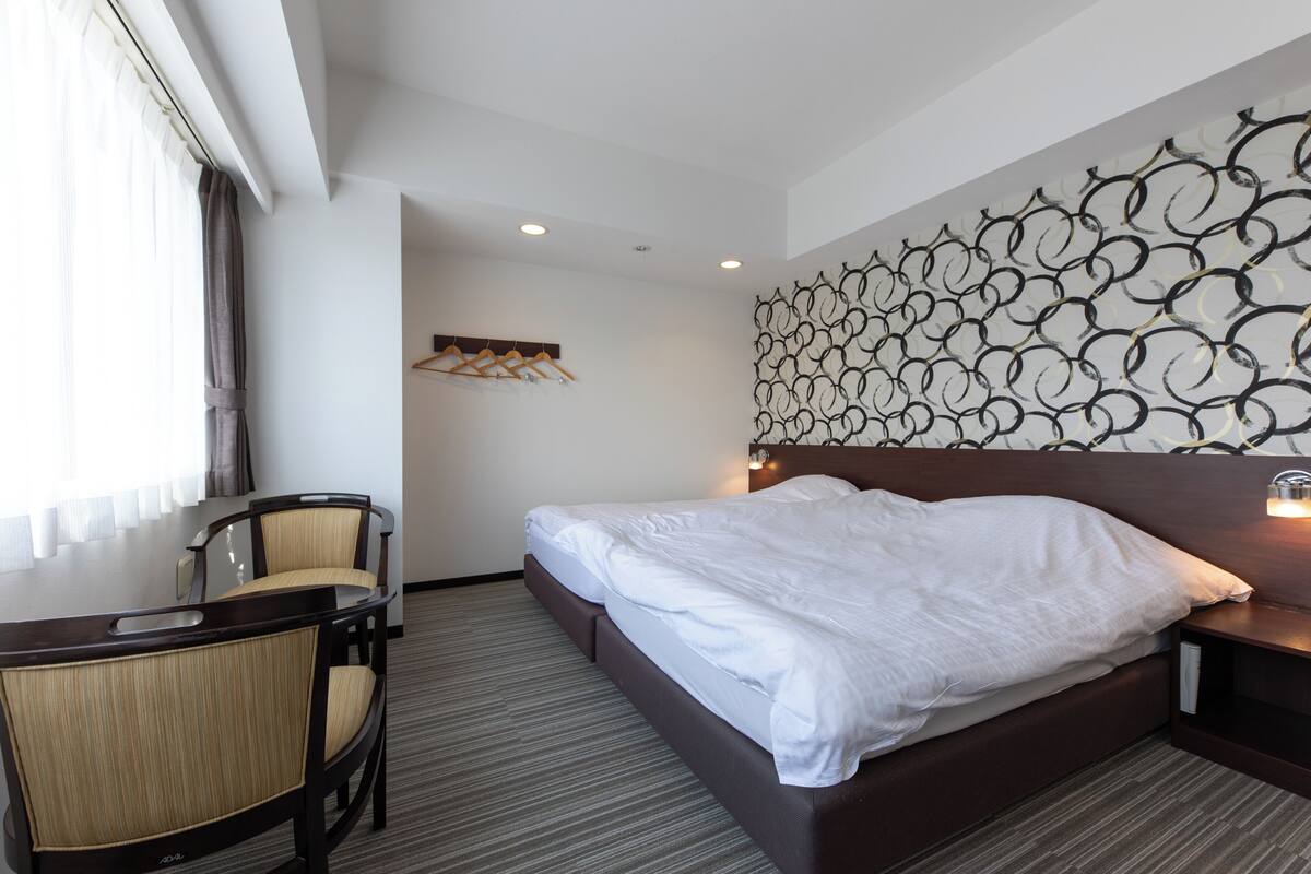 A hotel room with a bed, a desk, and chairs.