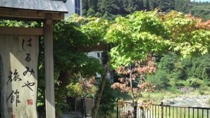 A traditional Japanese building with a wooden structure and a river in the background. - Harumiya Hotel (Fukushima)