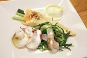 Un plato blanco con comida, incluyendo pescado y vegetales verdes.