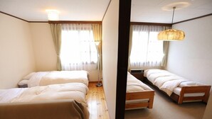 Ein Zimmer mit zwei Betten, Holzboden und einer Pendelleuchte.