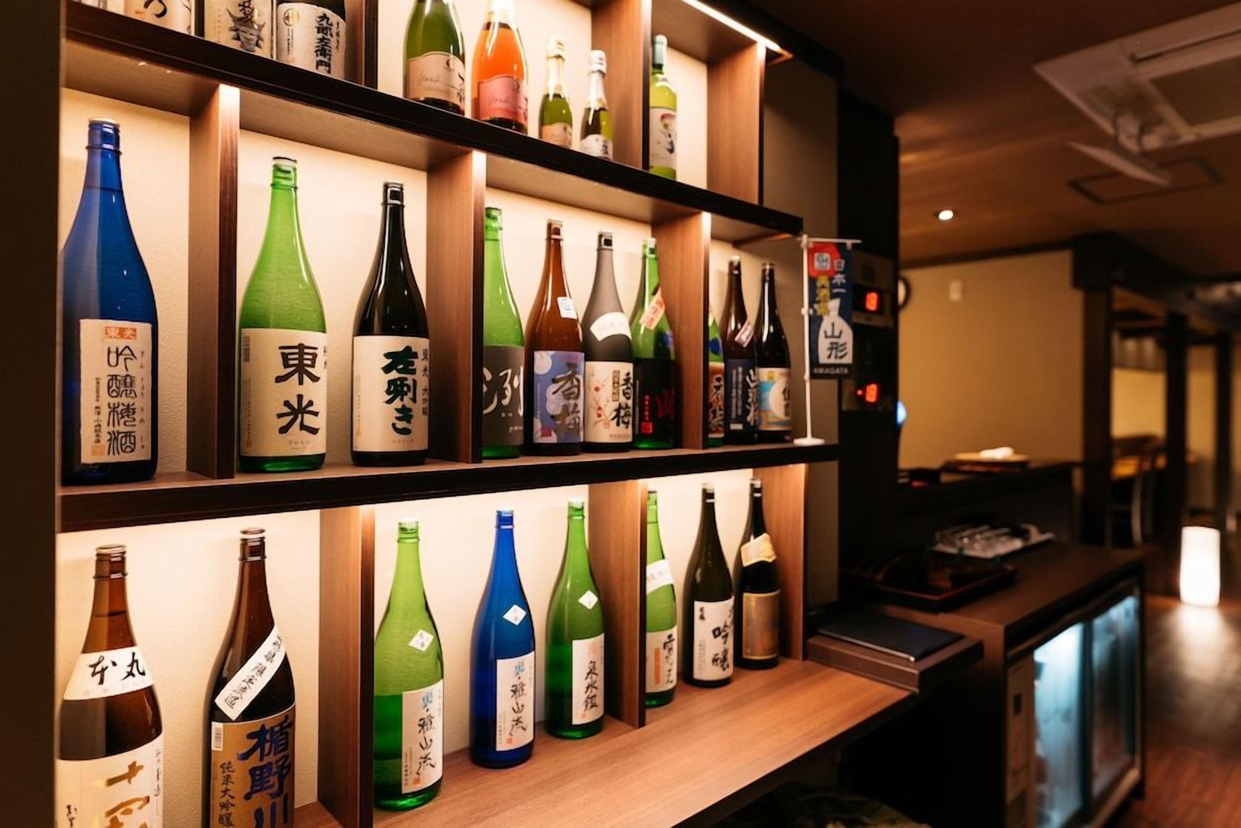 A shelf with various bottles of beverages, likely alcoholic, with labels in a non-Latin script, possibly Japanese.