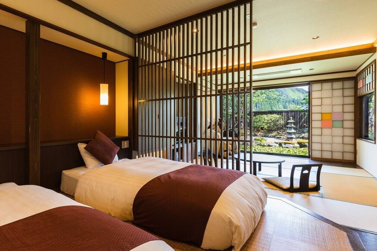 Una habitación de hotel con dos camas, vista a un jardín y una partición de estilo japonés tradicional.