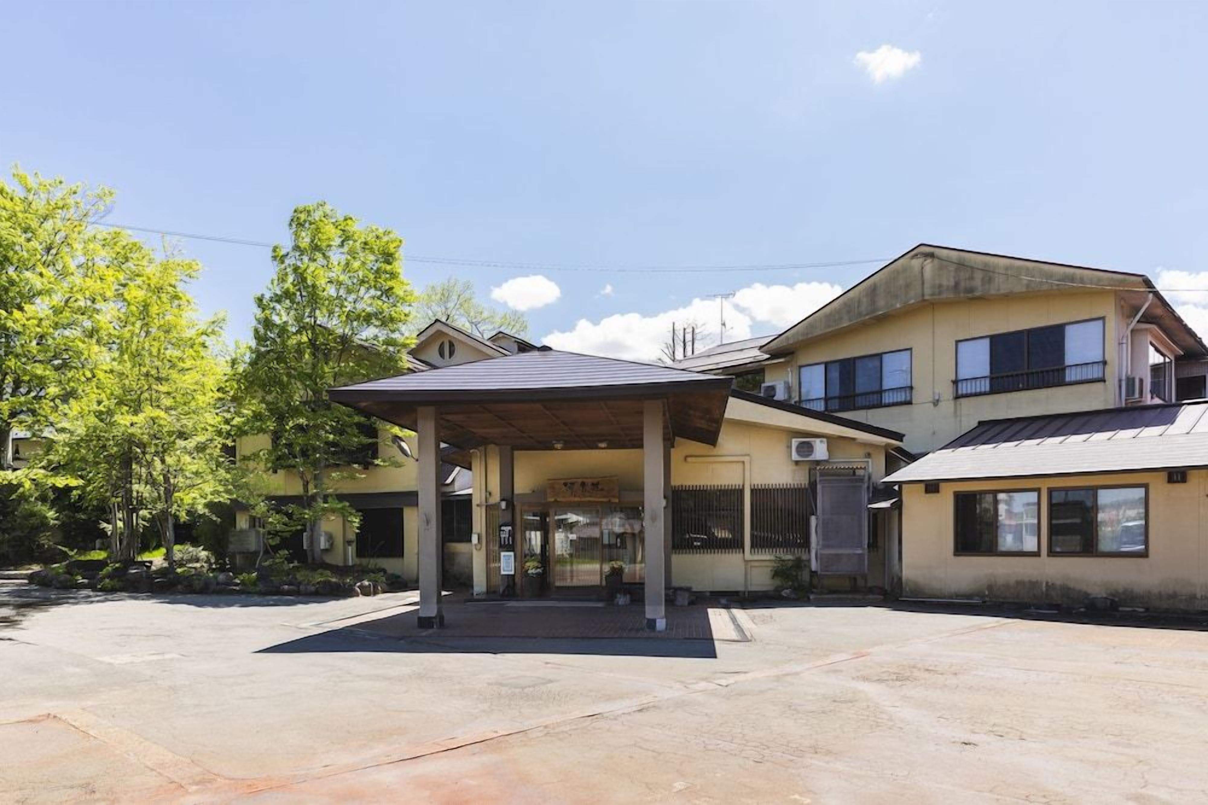 A two-story building with a covered entrance and a small adjacent structure.