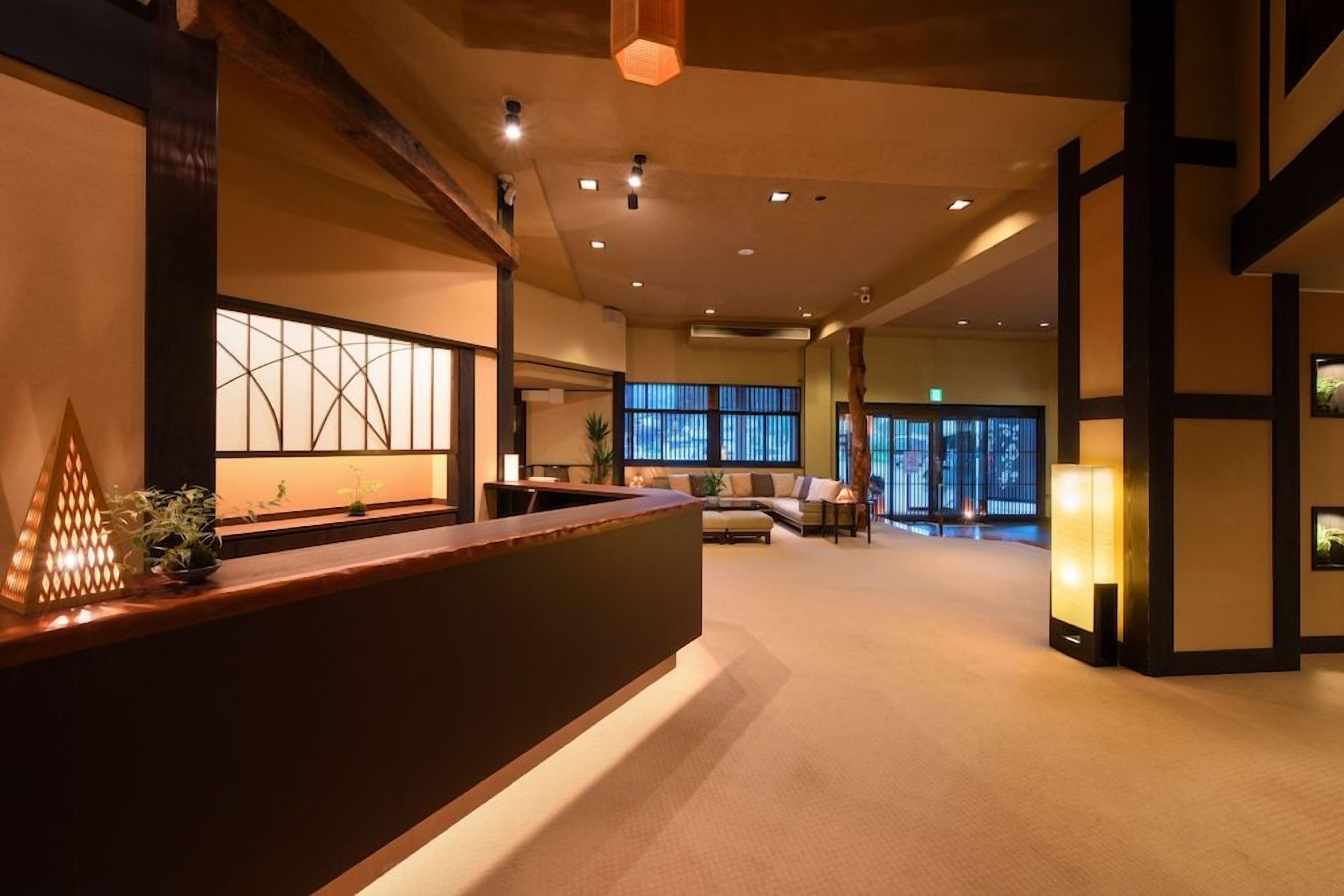 A reception area with a wooden reception desk, a large window with a view, and a seating area with a sofa and chairs.