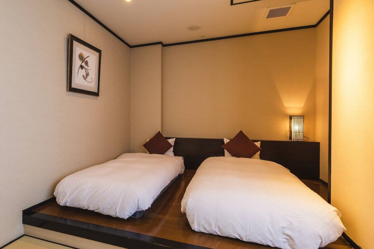 Una habitación de hotel con dos camas individuales, un cuadro enmarcado en la pared y una lámpara de noche.