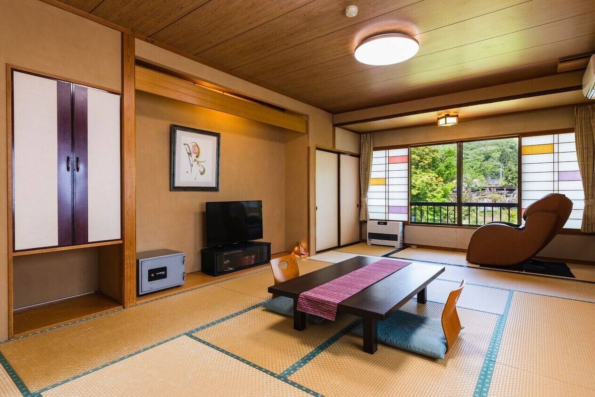 Una habitación japonesa tradicional con suelo de tatami, una mesa baja de tatami, un televisor y una puerta corredera.