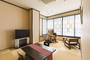 A modern living room with tatami flooring, a flat-screen TV, a massage chair, and a traditional Japanese-style sofa. - Kajikaso (Yonezawa)