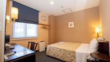 A hotel room with a bed, desk, chair, and a small table.