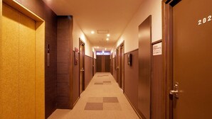 A hotel hallway with wooden doors, numbered 202, and a no-smoking sign.